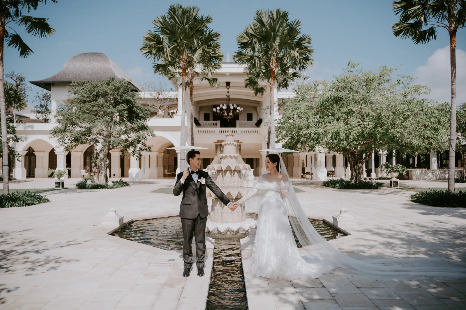 A couple in the courtyard at Jumeirah Bali, the water-palace architecture and palms rising behind them