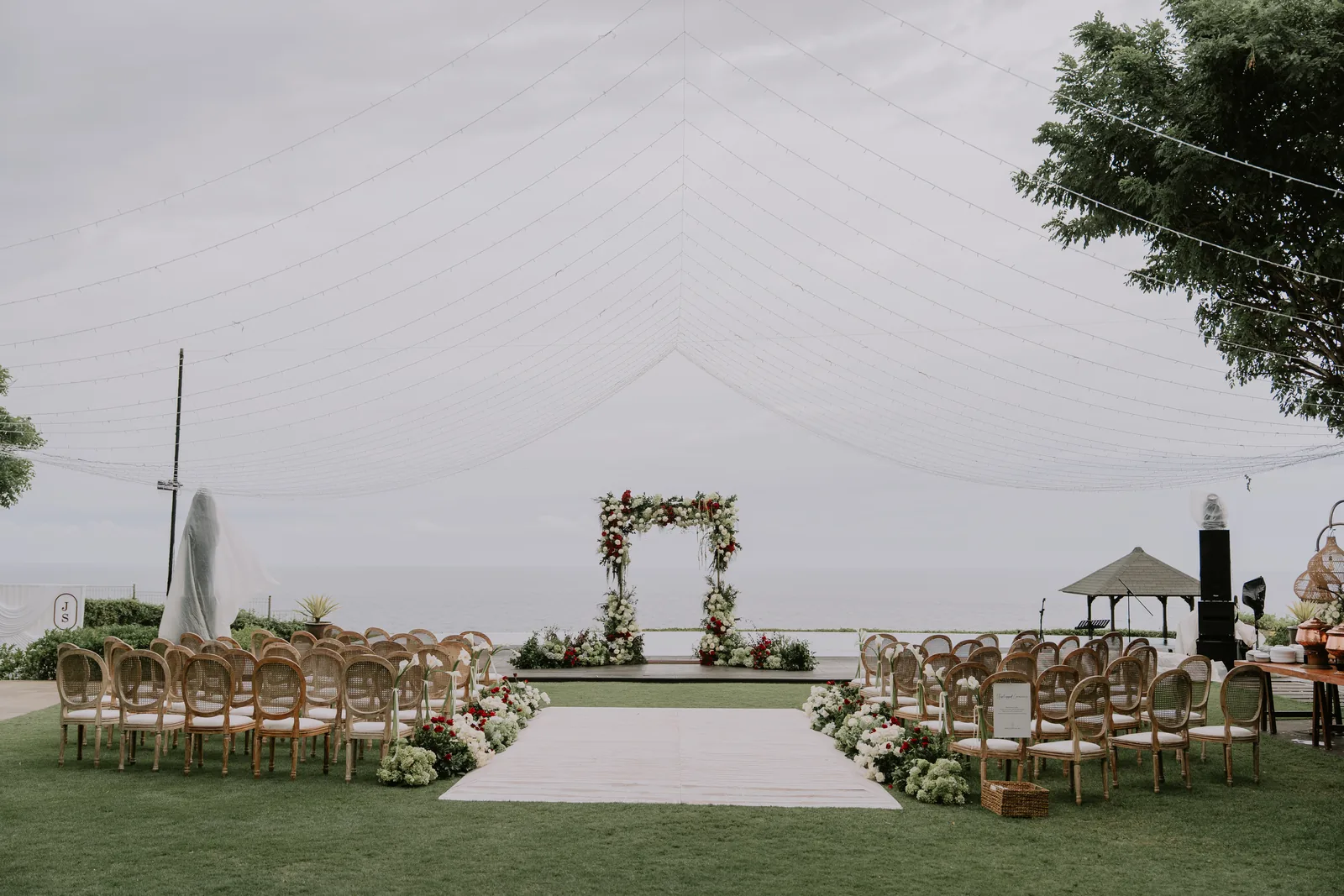 A marquee ceremony set on the lawn at Pandawa Cliff Estate, the floral arch facing the sea