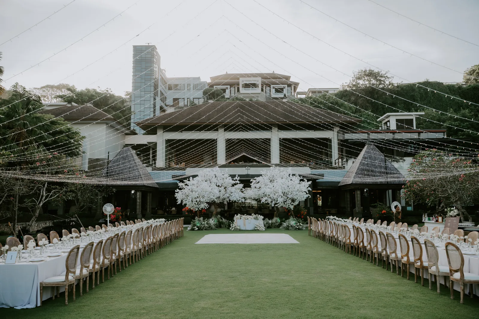 A ceremony inside the glass chapel at The Ritz-Carlton, Bali, guests standing as the couple exchange vows